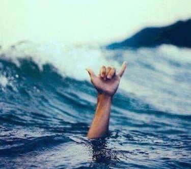 A hand coming out of the sea making a shaka