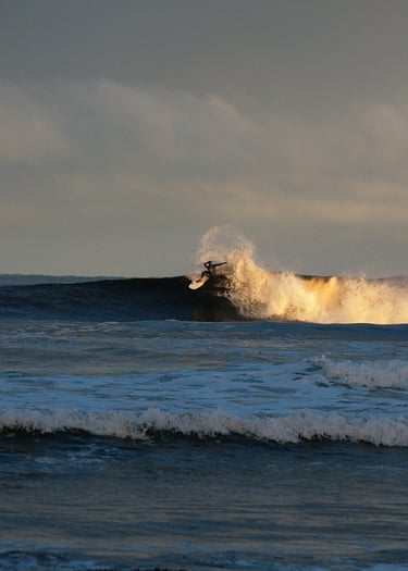 Surfing performing a snap with spray, early morning sunshine lighting uo the white water 