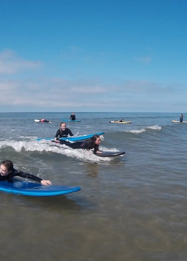 Two surfers paddling for a wave during Ysgol Tywyn activities day.