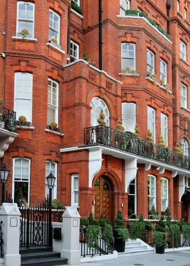 Classic London Mayfair luxury apartment building with arched windows and black iron balconies.