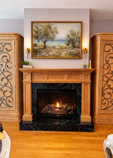 Custom stained wood fireplace mantel with black marble surround and decorative built-in cabinetry in