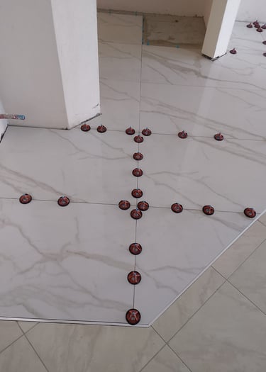 White marble porcelain floor tiles installed with a professional leveling system and spacers.