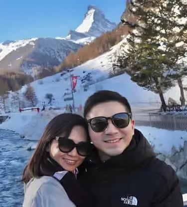 Happy couple taking a photo with the iconic Matterhorn backdrop while exploring Zermatt and hearing 