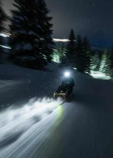 A person riding a sled down a snowy mountain at night with a bright headlight creating a motion blur