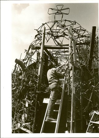 Howard Finster building the bicycle, an intricate junk sculpture art installation with metal scraps.