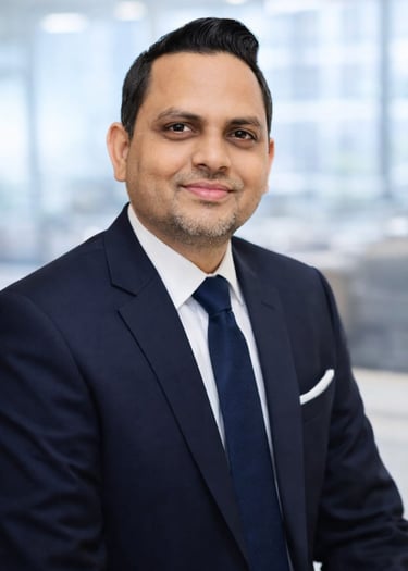 Professional corporate headshot of a smiling businessman in a navy blue suit and tie.