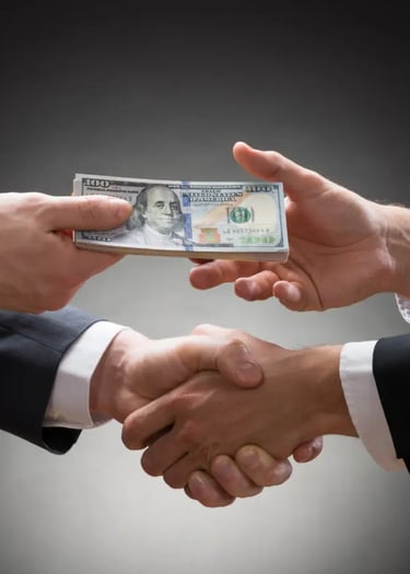 Two hands shake while one hand passes a stack investment money to the other.
