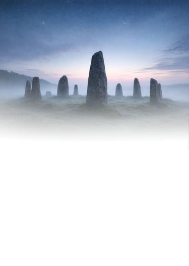 A circle of ancient standing stones rising from mist at first light, symbolising the turning year, c