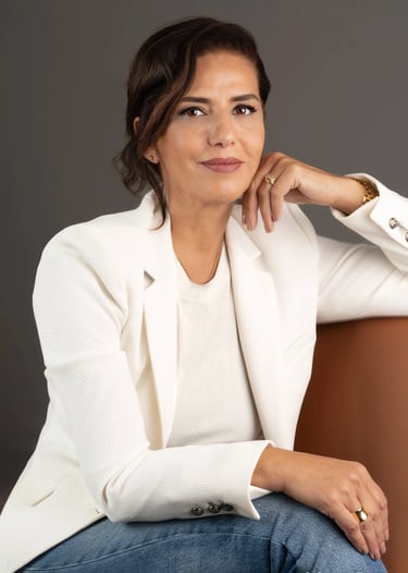 a corporate woman in a white jacket and jeans sitting on a chair