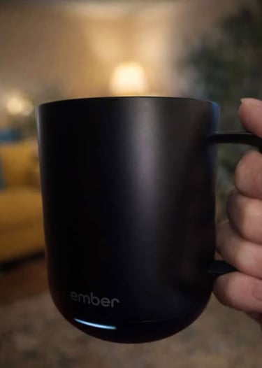 Hand holding a black temperature-controlled smart mug with soft ambient lighting in the background