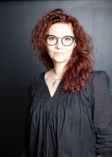 Marion Herlédan is a woman with red hair and glasses on a black background she is a food photographe