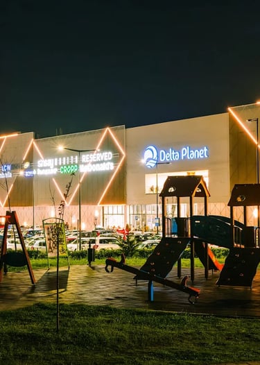 A modern playground illuminated at night in front of the Delta Planet shopping mall.