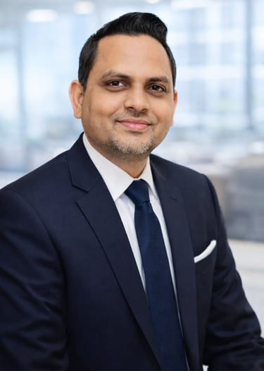 Professional corporate headshot of a smiling businessman in a navy blue suit and tie.