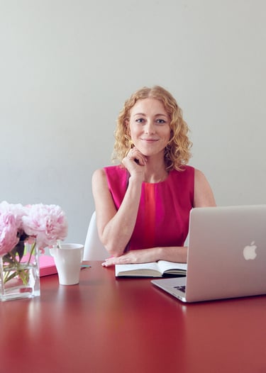 A blonde woman sitting behind a desk.
