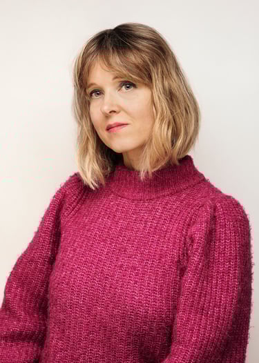 Porträt einer Frau in einem rosa Pullover, fotografiert in einem Studio.