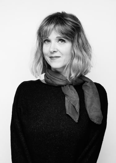 A black and white portrait of a blonde woman wearing a scarf.