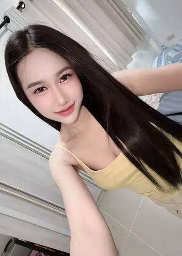 Smiling woman with long straight black hair wearing a yellow tank top in a bright room.