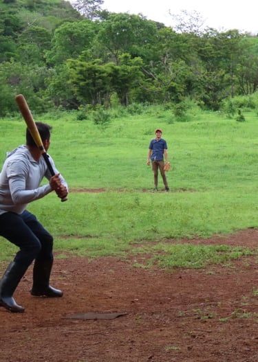 A group of young men playing baseball in a rural countryside.