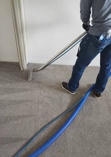 Technician steam cleaning carpet in Fort McMurray home.