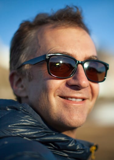 a man in sunglasses and a jacket is smiling