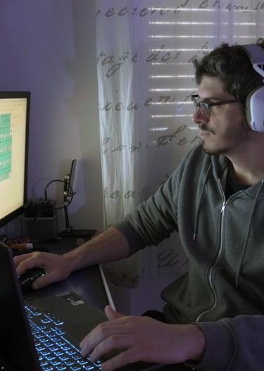a man wearing headphones and headphones, sitting at a desk with a laptop