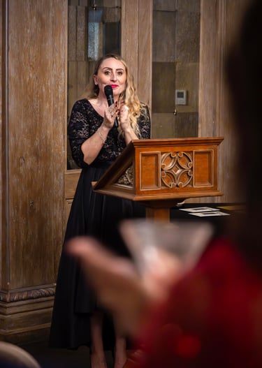 a woman in a black dress standing at a podium with a microphone