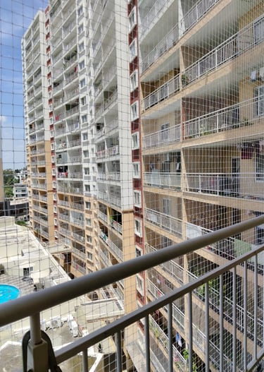 Technician from Sukumari Safety Nets fitting a pigeon net over a window frame.