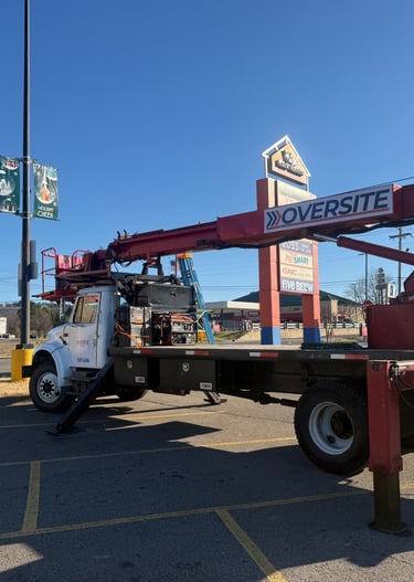 A commercial Oversite bucket truck parked in a shopping center lot for outdoor sign maintenance.