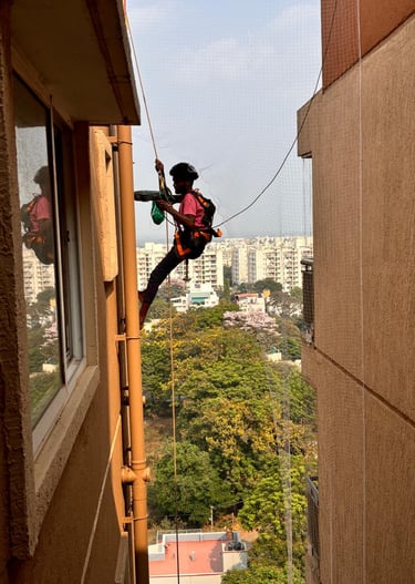 Wide shot of a residential building in Haralur with pigeon control nets visibly installed on ducts.