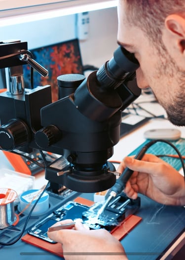 a man in a black shirt is looking at a microscope