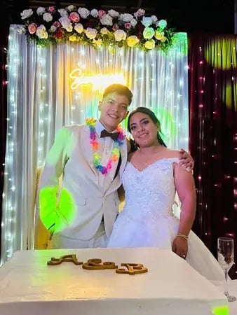 Pareja de novios celebrando boda frente al pastel durante evento con servicio de carnitas para invitados