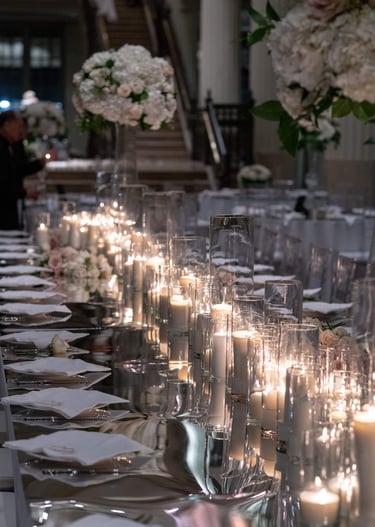 a long mirrored wedding reception table with candles and candles on it