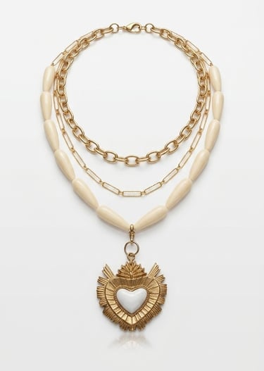 Layered gold chain necklace featuring ivory beads and a sacred heart pendant with white enamel.