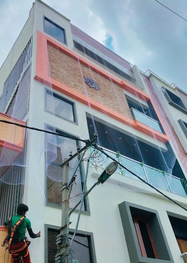 Technician carefully fitting a pigeon safety net on a high-rise apartment window in Mumbai.