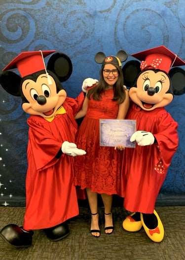 Mujer posando con Minnie y Mickey Mouse en graduación de Programa Internacional de Disney