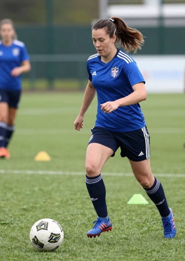 Close-up of a white British woman tying her football boots on an astro turf pitch, ready to play.