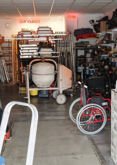 A well-stocked tool rental shop interior featuring cement mixers, ladders, and power tools on shelves.