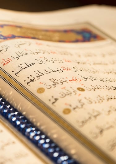 Close-up of an open Holy Quran with Arabic calligraphy and blue prayer beads on a page.