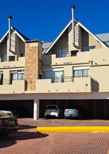 Modern multi-story apartment complex with gabled roofs and a ground-floor parking garage.