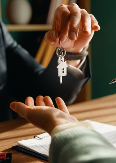 Real estate agent handing house keys to a new homeowner after signing a mortgage contract.