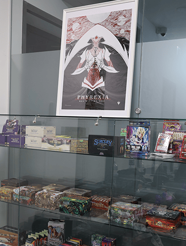 A display of TCG boxes, containing Flesh and Blood, One Piece TCG and more products.