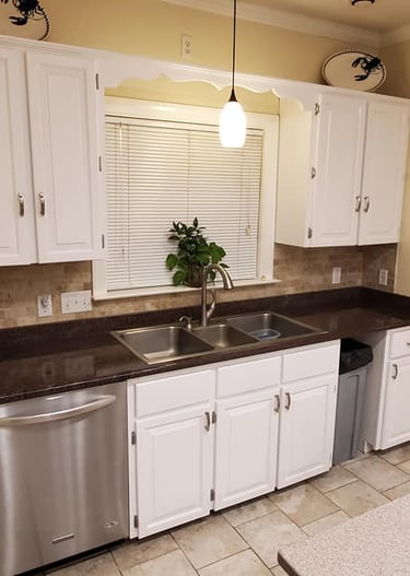 Modern kitchen remodel featuring white cabinets, dark granite countertops, and a stainless steel double sink.