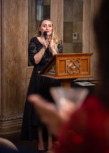 a woman in a black dress standing at a podium with a microphone