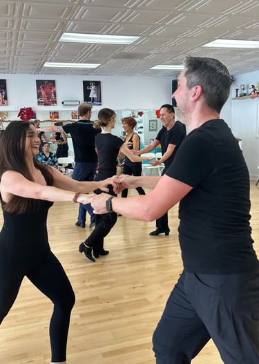 A joyful ballroom dance class at McCann Dance, where students of all levels learn social dance
