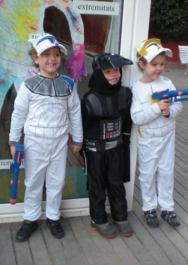 Three young children dressed in Star Wars costumes posing outside with toy blasters.