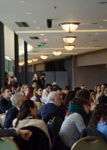 a group of people sitting at tables in a room Haciendo gestión