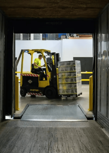 Forklift operator loading pallet into truck at warehouse — efficient delivery and logistics handling