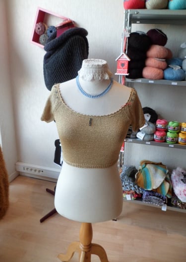 Petit haut demi saison tricoté à la main dans un fil doré avec des finitions au crochet 