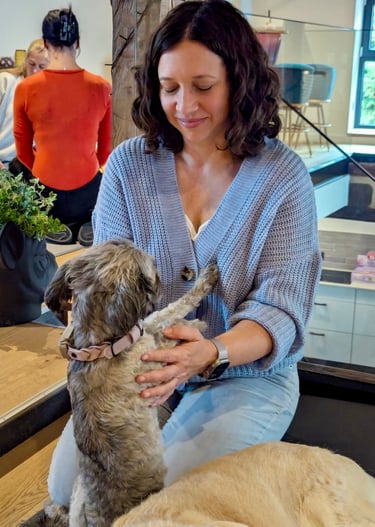 Svenja sitzt im Fersensitz, währen Pudel Paula ihr die Vorderpfoten auf die Brust legt.