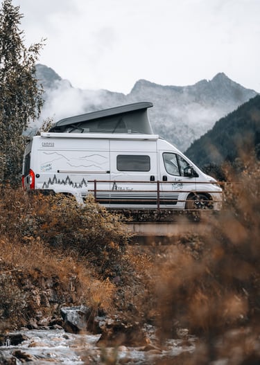 a van parked in a field with mountains in the background